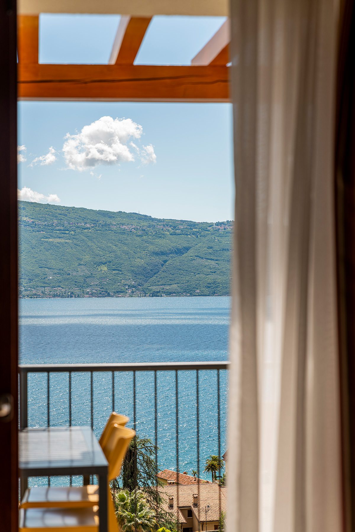 Balcone con tavolo e sedie, vista lago e montagne al sole