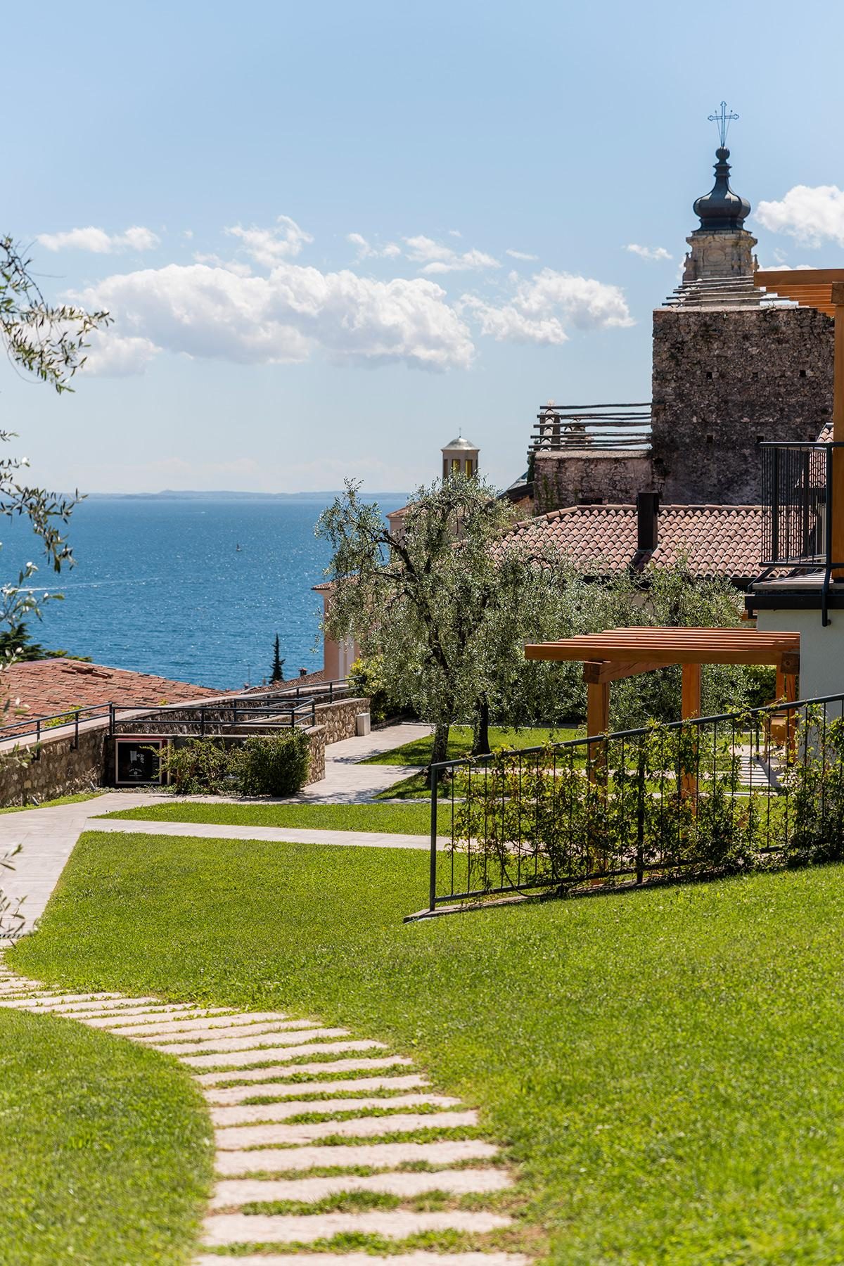 Gartenweg mit Olivenbaum, Seeblick und Kirchenansicht