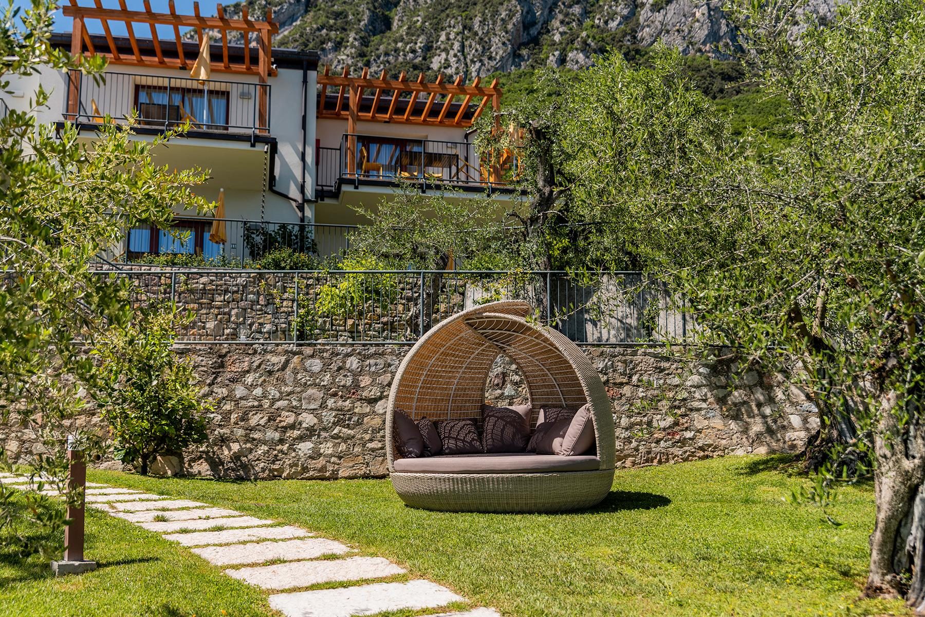 Giardino con poltrona a nido in rattan, ulivi e vista montagna