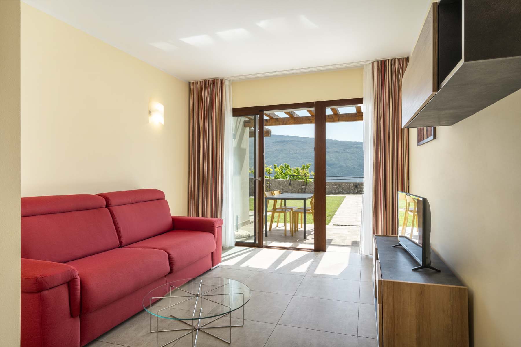 Bright living room with red sofa, TV and patio mountain view.