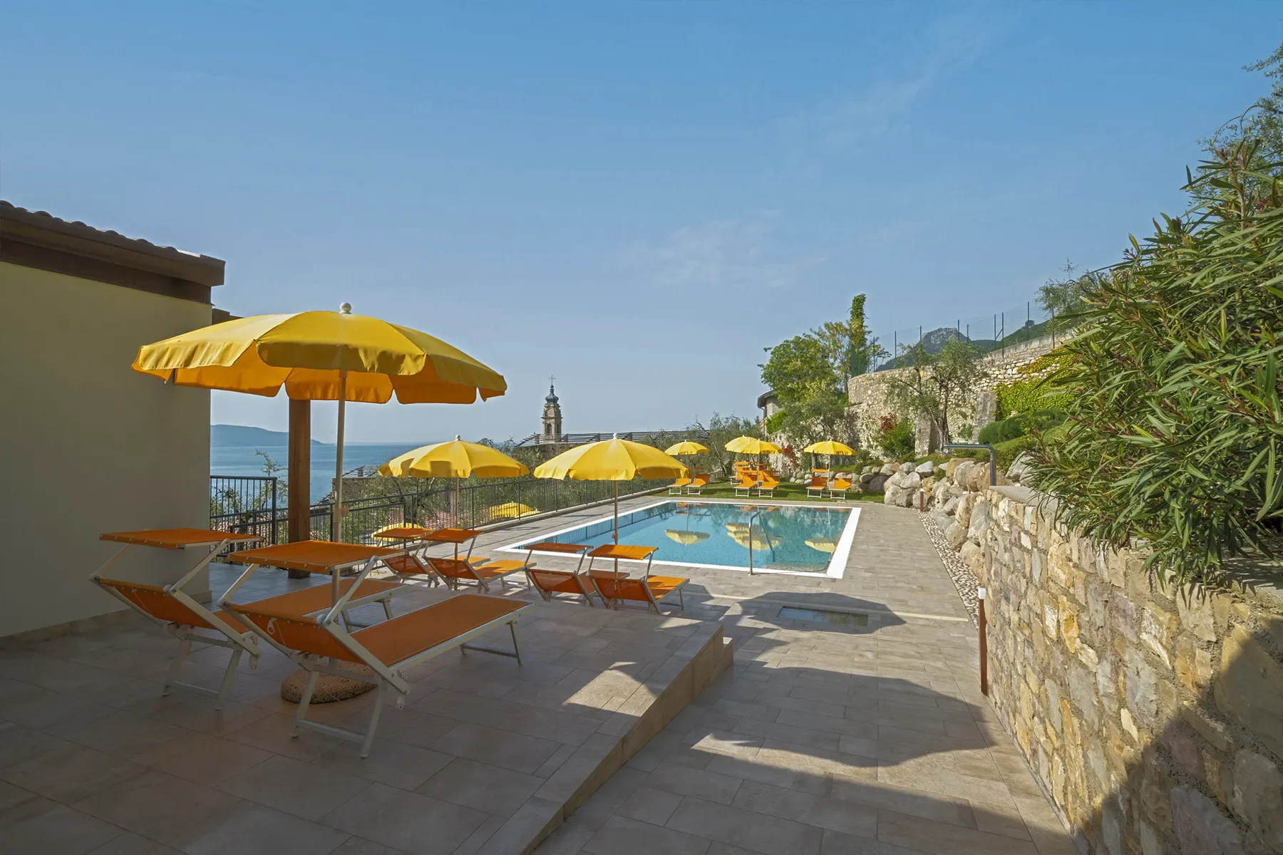 Outdoor pool with yellow umbrellas and sun loungers, lake view