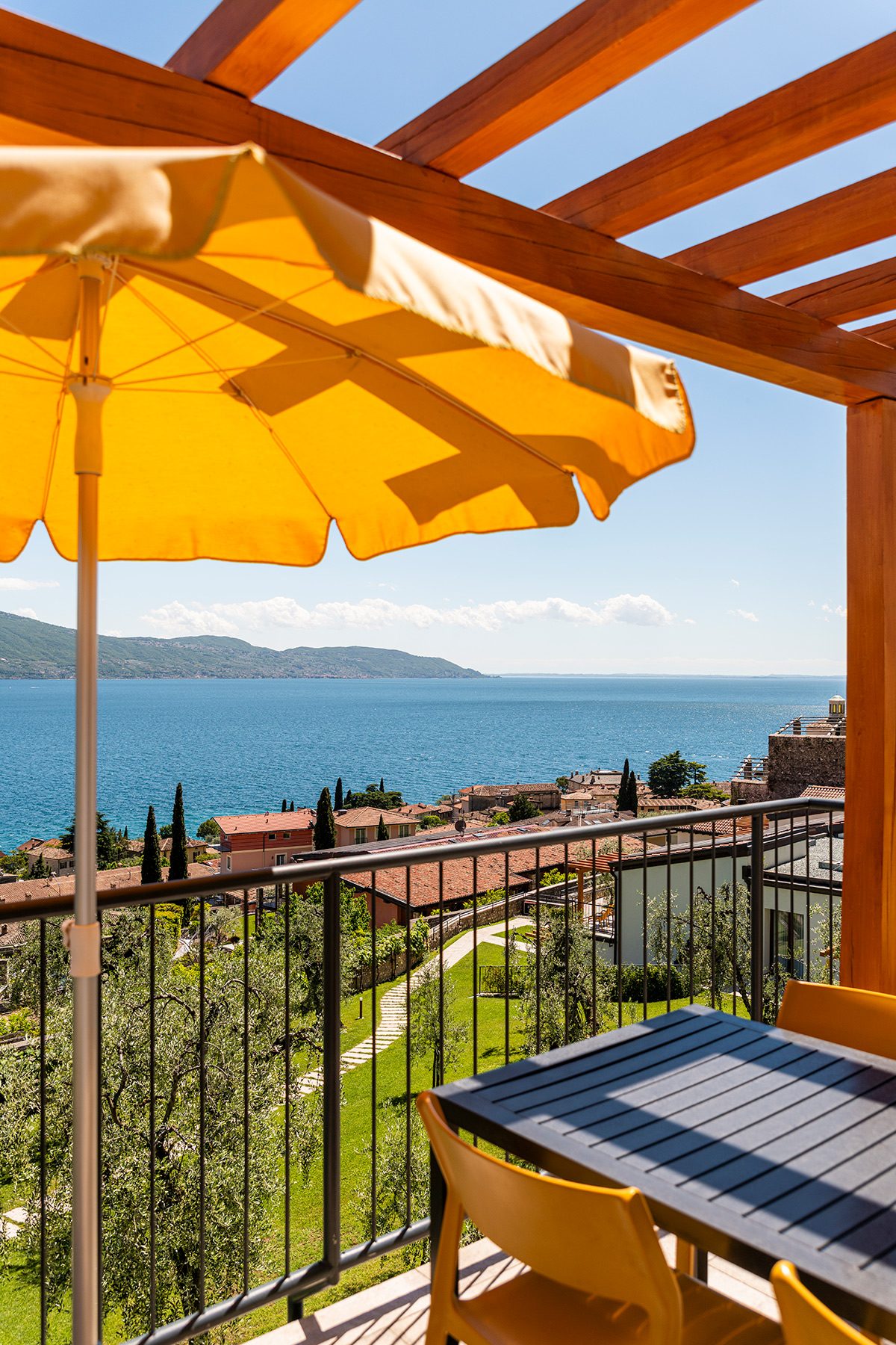 Sonnige Terrasse mit gelbem Schirm und Seeblick über den Ort