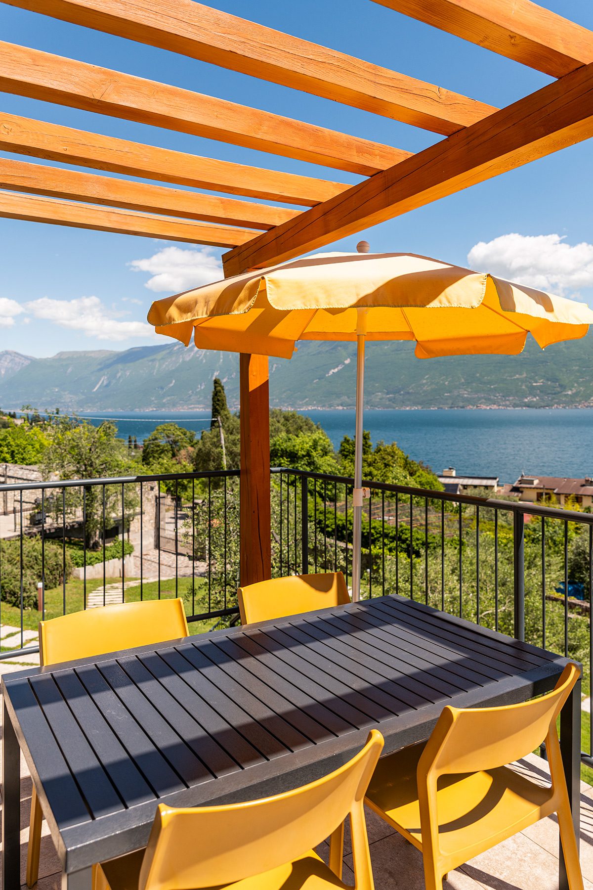 Terrace table with yellow umbrella, lake and mountain view.