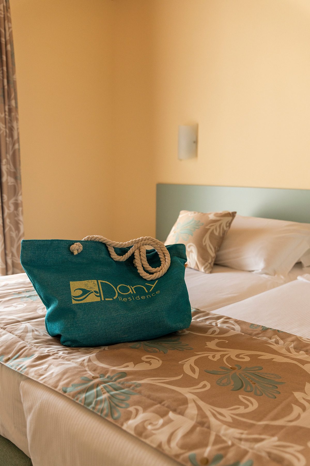Türkise Stofftasche mit Seilgriffen auf ordentlich gemachtem Bett