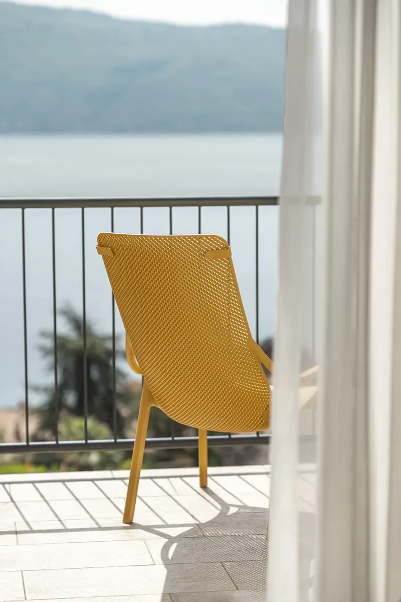 Yellow mesh chair on a balcony overlooking a lake and hills